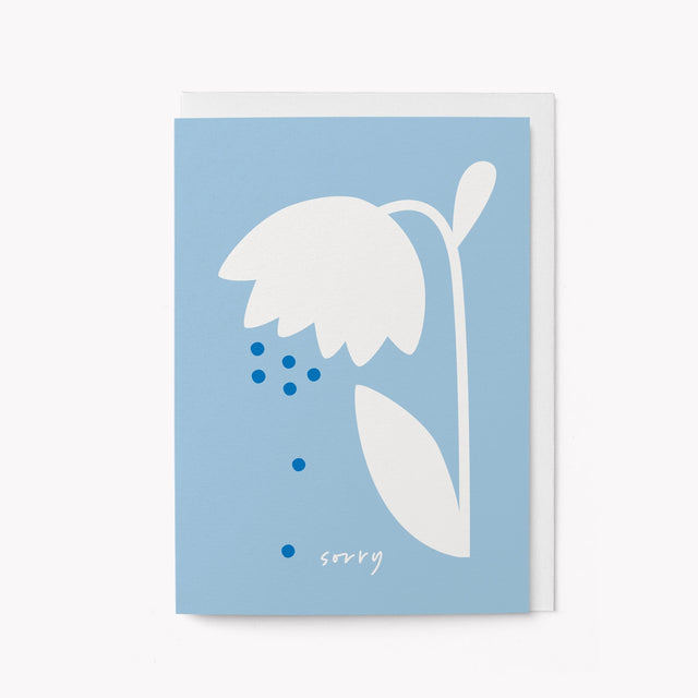 Framed artwork with a white flower and blue dots on a light blue background