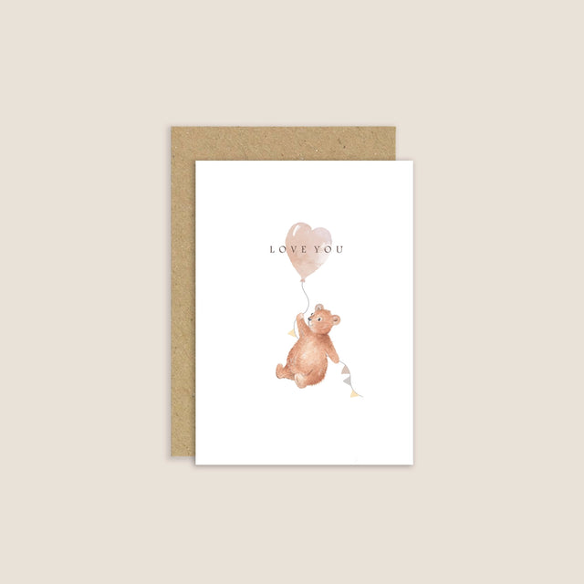 Greeting card with a bear holding a heart-shaped balloon and 'Love You' text on a beige background.
