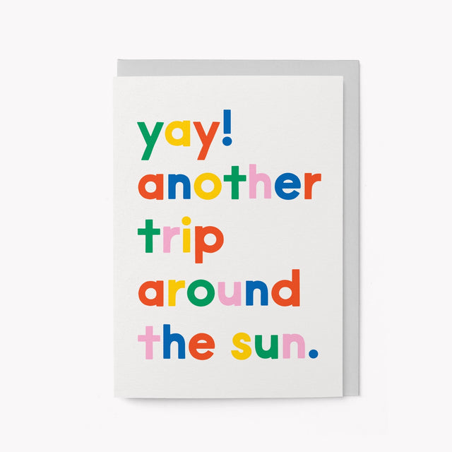 Colorful text card with 'yay! another trip around the sun.' on a white background