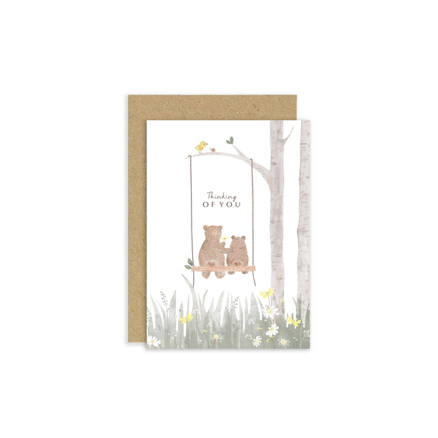 Greeting card with two bears on a swing under a tree, with 'Thinking of You' text, on a white background.