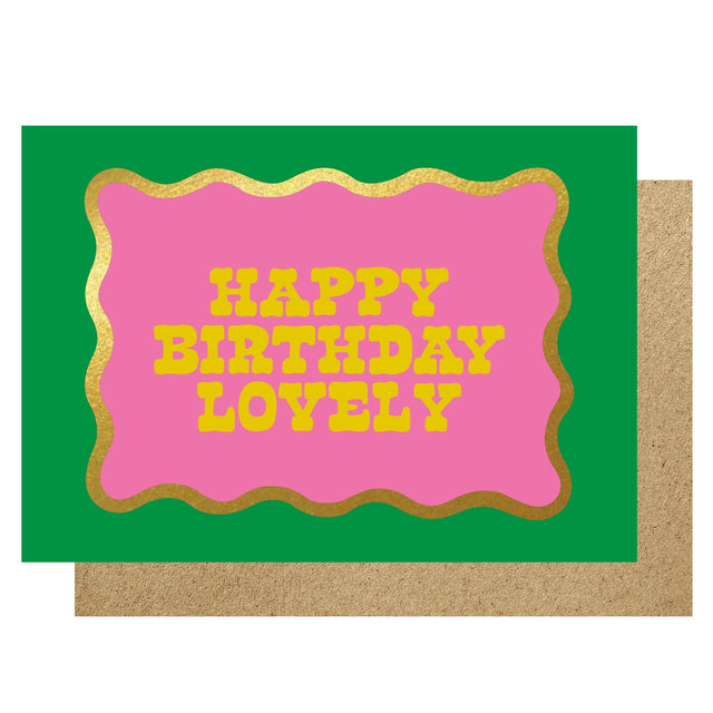 Greeting card with 'Happy Birthday Lovely' text on a pink background with gold border, on a green card with brown envelope.