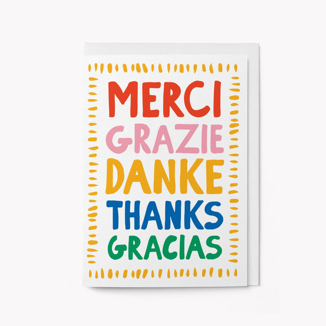 Multicolored card with 'Merci Grazie Danke Thanks Gracias' text on a white background